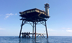 Learn More & Get Involved
· Teens4Oceans
Above water overlooking the Mid-Atlantic Ocean, this camera gives us a bird’s eye view of the ocean surrounding the Frying Pan Tower. When weather moves in, you’ll see a swift change in the waves and want to watch the storm roll through. On other days, the sunrise, sunset, and expansive clouds on the horizon will be dramatic highlights to your day. Groups travel to the Frying PanTower regularly for dive trips, volunteer restoration work, or vacation. Travel to the tower happens by boat or by helicopter, with the helicopters landing on the helipad in clear view of the camera. How do people get to the main level from a boat? They are raised by a hoist in a lift certified bosun’s chair. 
