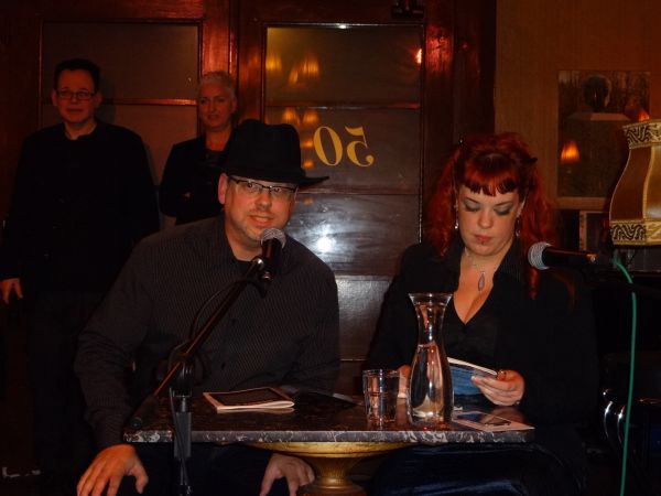 Charly Blood und Zöe Angel lesen; im Hintergrund links: der Verleger