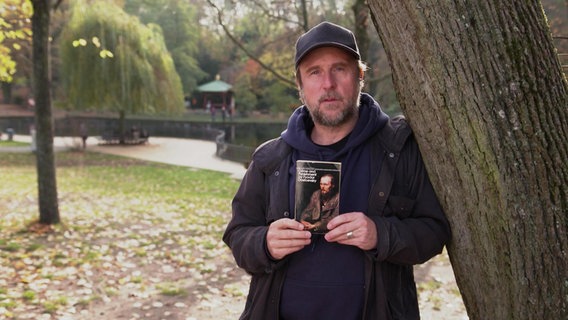 Bjarne Mädel mit Buch im Park.  