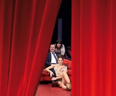 Eine Theatergruppe hinter einem roten Vorhang