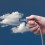 Eine Hand steckt ein LAN-Kabel in eine Wolke im Himmel