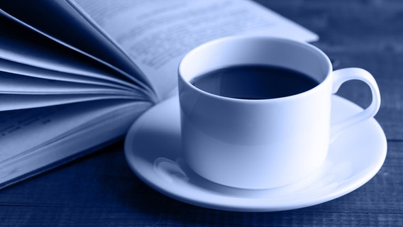Aufgeschlagenes Buch und eine Kaffeetasse © fotolia.com Foto: Africa Studio