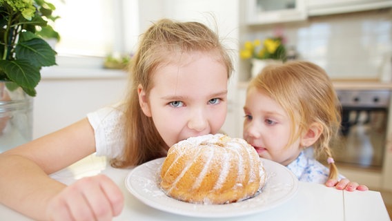 Kinder naschen von einem Kuchen, der vor ihnen auf einem Tisch steht. © picture alliance / Zoonar Foto: Robert Kneschke