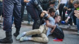 A man identified as Georgy Oganezov is forcibly detained by Russian riot police in Moscow on August 3 as Timur Olevskiy, an anchorman for Current Time, interviews him.