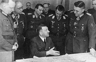 Hitler im März 1945 an der Ostfront in einer Lagebesprechung. Er war gezeichnet von seiner Parkinson-Krankheit und konnte nicht mehr länger als eine halbe Stunde stehen; die zitternde linke Hand ist unter dem Kartentisch verborgen. Neumann&amp;Eberle: 