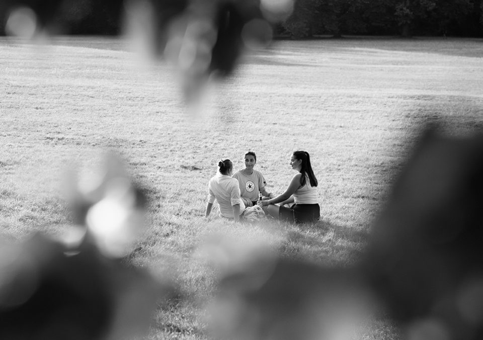 Drei Frauen sitzen im Kreis auf einer Wiese beim Interview