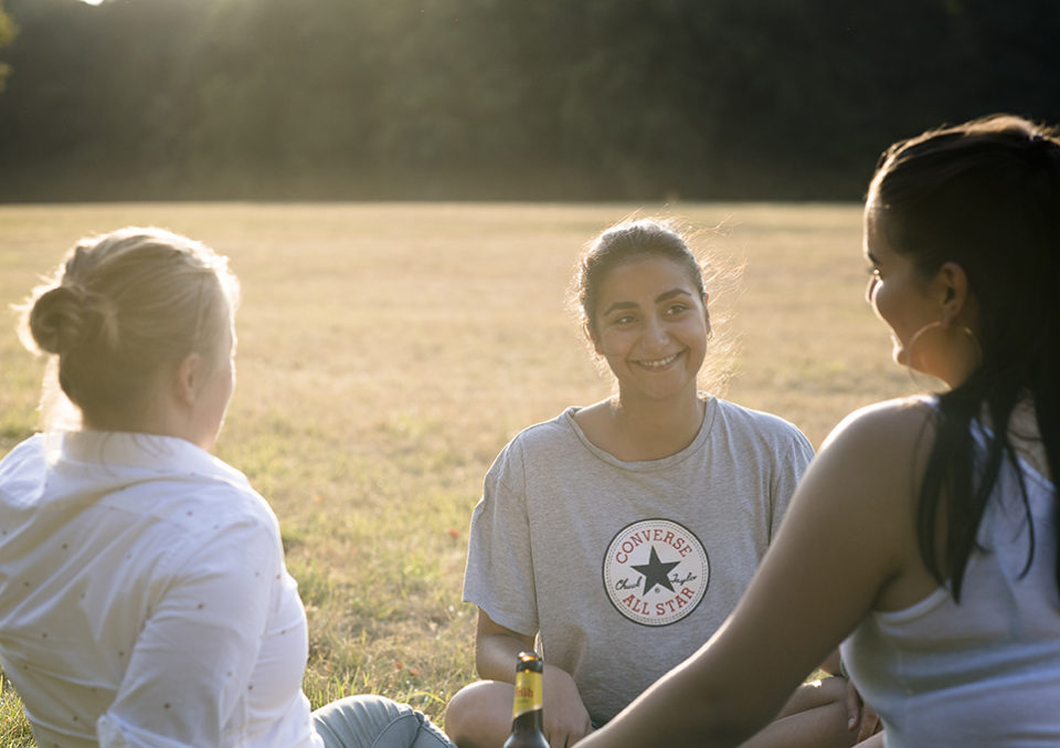 Drei Frauen sitzen im Kreis auf einer Wiese beim Interview