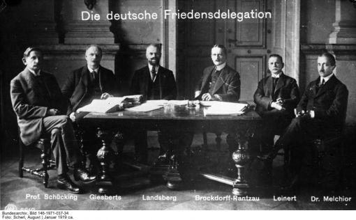 Deutsche Verhandlungsdelegation Auf der Pariser Friedenskonferenz wird der Friedensvertrag von Versailles geschlossen. Damit endet der am 11. November 1918 mit dem Waffenstillstand von Compiègne zu Ende gegangene 1. Weltkrieg auch völkerrechtlich. Die deutsche Delegation (im Bild) darf nicht an den Verhandlungen teilnehmen und kann nur am Schluss der Konferenz noch einige Änderungsvorschläge einbringen. Im Vertrag wird Deutschland allein für den Ausbruch des 1. Weltkrieges verantwortlich gemacht. Zu den Unterzeichnern gehörten die USA, das Vereinigte Königreich, Frankreich, Italien, Japan, Belgien und andere. Deutschland wird zu Abrüstung, Gebietsabtretungen (u. a. Elsass-Lothringen, weite Teile Westpreussens, Provinz Posen) und Reparationszahlungen verpflichtet. Die Mehrheit der Deutschen empfinden den Vertrag als demütigendes Diktat. Unter Protesten unterzeichnete Deutschland schliesslich den Vertrag am 28. Juni 1919. Der Vertrag gilt auch als Gründungsakte des Völkerbundes. (Bild: Deutsches Bundesarchiv, Fotograf: August Scherl, 1919, Bild 146-1971-037-34)