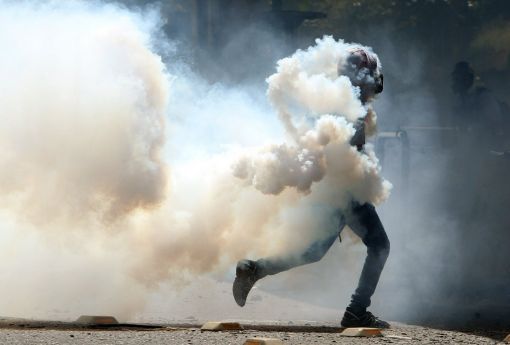 Venezuela Die Demonstrationen gegen Präsident Nicólas Maduro werden immer gewalttätiger. Täglich gehen in der Hauptstadt und andern Städten Zehntausende auf die Strasse und fordern sofortige Neuwahlen. Die Demonstrationen dauern seit Wochen. Wegen des tiefen Ölpreises und der Misswirtschaft der Regierung leidet Venezuela unter einer horrenden Wirtschaftskrise mit dramatischen Versorgungsengpässen. Die Opposition hat die Armee aufgerufen, sich von Maduro zu distanzieren. Doch die Generäle, die grosse Privilegien geniessen, halten nach wie vor zum sogenannt sozialistischen Präsidenten. Im Bild ein Demonstrant in Caracas, eingehüllt in Tränengas. (Foto: Keystone/EPA/Mauricio Duenas Castenada)