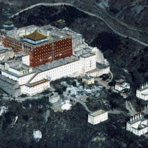 Potala Pastiche in Chengde, China
Die Mandschu-Kaiser, die Dynastie der Qing, verbrachten während des ganzen 18. und eines Teils des 19. Jahrhunderts die Sommermonate jeweils 250  km nordöstlich von Peking in Jehol, dem heutigen Chengde; es war dann zeitweilig Chinas Hauptstadt. Kaiser Kangxi begann 1703 mit dem Bau seiner Sommerresidenz – Bishushanzhuang, „Bergdörfchen, um der Hitze zu entfliehen“.

Ein Dörfchen war der kaiserliche Sommersitz ja nun gewiss nicht. Eine 25 km lange Mauer umgürtete ausser dem eigentlichen Palast und den zugehörigen Pavillons einen Landschaftsgarten mit 72 „szenischen Wundern“ – eine Art China en miniature, mit Seen, Hügeln und Ebenen. Kangxi und später sein Enkel, Kaiser Qianlong, legten ausserhalb des kaiserlichen Parks elf Tempelklöster an, darunter Imitationen von tibetischen Lamaklöstern. Ein Ballenberg der andern Art also – oder zeitgeistiger: ein „theme park“ – , freilich mit Hintergedanken. Die beschwichtigende Verbeugung nach Norden galt dem mächtigen mongolischen Klerus. „Besser ein Kloster als 10 000 Soldaten“ wird Kaiser Qianlong zitiert.

Die grösste Anlage, der Putuozongsheng, auf einem 220 Hektar grossen Gelände in den Jahren 1767 bis 1771 erbaut, ist dem Potala, der Palastburg des Dalai Lama in Lhasa im Masstab 1:2 nachempfunden. Die Festung aus rotem Backstein umschliesst einen mit vergoldeten Ziegeln überdachten Tempel; zwei Dutzend weisse Häuser – Mönchswohnungen, Nebengebäude – sind über den Hang vor dem Hauptbau gestreut. Häufige und heftige Gewitter gehören in Chengde zum sommerlichen Ungemach.

1820 traf ein Blitz Kaiser Jiaqing, damit war für den Sommersitz der Lack ab. Der Hof zog wieder das schwüle Peking der Sommerfrische im Bergdörfchen vor. Die Unesco zeichnete Chengde 1994 aus – und beförderte gleichzeitig mit der kaiserlichen Sommerresidenz auch den originalen Potala, die vormalige Winterresidenz des Dalai Lama, zur Welterbestätte. Jahr der Aufnahme: 1987. (Copyright: Georg Gerster/Keystone)