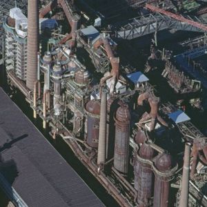 Die Völklinger Eisenhütte im Saarland
Die Industriearchäologie hat ein erstaunliches Sortiment von Hochöfen, Gasometern, Kokereien, Maschinen-Raritäten und Kuriositäten, Spinnereien, Fördertürmen, Wasserradsägereien. Schleusen und Hebewerken, Stollenmundlöchern, Zechen und Pumpenhäusern in die Kulturgeschichte heimgeholt. In Gasgebläsehallen finden Rockkonzerte statt, Kraftwerke und Wassertürme werden Ausstellungsräume – Umnutzungen sind für Industriedenkmäler überlebenswichtig. Aber Umnutzung allein veredelt sie bestenfalls zu rostenden Ravioli mit Kulturfüllung.

Umwertung ist angesagt: die Meilensteine der Technikgeschichte sind selber Delikatessen der Kultur – und die Unesco vergibt seit l978 das Prädikat „Welterbe“ auch an die Inkunabeln der industriellen Revolution. So kam die deutsche Völklinger Eisenhütte im Saarland, die Aufstieg und Niedergang des Industriezeitalters spiegelt, 1994 auf die Liste – ein Quantensprung im Verständnis von Kultur. Ein Mammut der Industriegeschichte, stillgelegt, aber gleichsam schlüsselfertig, alles andere als Schrott, komplett ausgerüstet, Erzbunker und Kokerei, Sinteranlage, Hochöfen und so fort, fand sich wieder in der Gesellschaft von Taj Mahal, Borobudur und Notre-Dame.

1873 gegründet, hatte die Eisenhütte in der hüttenmännischen Technik Marksteine gesetzt, ihre Innovationen und Pionierleistungen gaben weltweit zu reden, aber die Marktsituation erzwang trotzdem 1986 den letzten Abstich, die Hochofenanlage zur Roheisenerzeugung machte dicht.

Seit 2000 ist die Anlage in der Obhut einer „Bauhütte der Hütte“, die ihre Nutzung als Museum und für Kulturveranstaltungen regelt und mit Argusaugen ihre technische Authentizität behütet. 400 000 Besucher im Jahr 2011 überzeugten sich von deren pingeliger Wachsamkeit. So etwa: keinesfalls zu viel Rost – aber auch nicht zu wenig... Jahr der Aufnahme: 2002. (Copyright: Georg Gerster/Keystone)
