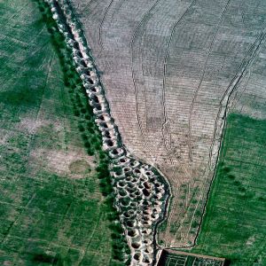 Heroische, mörderische Brunnen
Trotz - oder vielleicht gerade wegen seiner sengenden Wüsten ist Iran eine hydraulische Zivilisation: am Wasser hängt, zum Wasser drängt doch alles. Für dessen Fassung, Transport, Speicherung und Verteilung ist das Qanat-System eine heroische, mörderische Errungenchaft.

Die Qanate sind horizontale Brunnen. Sie zapfen unterirdisch das Grundwasser in den Schwemmfächern am Gebirgsfuss an und leiten es unter Ausnutzung des natürlichen Gefälles an die Oberfläche. Der Stollen verläuft so, dass seine Neigung geringer ist als die Neigung des Geländes. Wenn das Wasser am Ende des Stollens austritt, versorgt es Felder, Siedlungen, Städte. Der Garten in der iranischen Provinz Fars (unser Bild) hängt an seinem Qanat wie an einem Tropf.  Die Geländeverhältnisse bestimmen die Länge der  Stollen, sie dürfen nur ein minimales Gefälle haben, ideal ist 1 Millimeter je Meter, zu schnell fliessendes Wasser erodiert die Sohle. Schächte in Abständen von wenigen bis zu 40 Metern belüften die Stollen. Sie dienten auch deren Aushub und ermöglichen den Unterhalt, Die Schachtöffnungen, manchmal krakelig, manchmal soldatisch aufgereiht, punktieren die persische Landschaft. Die Stollen laufen unterirdisch viele Kilometer weit, bis sie sich mit der Oberfläche schneiden. In Zentraliran soll es 80 Kilometer lange Qanate geben, die tiefsten – in der Provinz Khorasan – beginnen angeblich 400 Meter unter der Oberfläche....Schätzungen, die sicher mit einem Körnchen Salz zu geniessen sind, Aber auch nach Abzug von einigen Kilometern und Metern bleiben solche Anlagen phantastische, ans Unglaubliche rührende Leistungen. Bau und Unterhalt sind reine Wühlarbeit, geleistet mit keinen andern Hilfsmitteln als Hacke, Handschaufel und Ledereimer, in dem das gelockerte Material ausfährt. Über dem Aushub eines langen, tiefen Qanats müssen Jahrzehnte vergangen sein. Der Vortrieb des Stollens erfolgt ohne Zimmerung oder irgendeine Sicherung. Dauernd drohen Einsturz und. namentlich am Kopfende Wassereinbruch; der Gedanke an die häufigen Erdbeben foltert – und auch die Vorstellung von den Giftschlangen, die immer wieder einmal in den Qanatstollen plumpsen, hebt die Stimmung nicht.  (Ich spreche aus Erfahrung, wenn auch der Qanatstollen, in den ich mich abseilen liesss, nur 20 Meter tief lag.) Öllampen dienen als Arbeits- und Warnlichter: ihr Erlöschen signalisiert Sauerstoffarmut.  Das Maulwurfsdasein der Qanatarbeiter (muqanni) ist Stoff für Albträume.  

Schon möglich, dass es im Trockengürtel der Erde noch mehr     Wassergewinnungsverfahren von vergleichbarer Genialität gibt – keine kann aber ganz so von der Verzweiflung inspiriert sein wie die Qanat-Technik. Ein französischer Geograph nannnte diese einmal „die heroische Lösung“. Die Iraner, seit Jahrtausenden Spezialisten im Qanatbau und wohl dessen Erfinder, wissen es am besten: „Mörder“ schimpfen sie manchmal ihre Qanate. Mit Grund: bei der Maulwurfsarbeit, die Stollen und Schächte mit einem Kilometertotal produzierte, das zu einer Mondreise – hin und zurück – ausreichen würde, müssen Ungezählte umgekommen sein. Tausende ertranken, Zehntausende wurden verschüttet. Eben: eine Mordsarbeit.

Die Verbreitung des Qanatbaus über den halben Globus im Laufe von Jahrtausenden ist ein Beispiel für Technologietransfer. Einwurzeln konnte der Technikimport natürlich nur dort, wo ähnliche klimatische, topographische und hydrologische Voraussetzungen betanden. Schon am Ende des 8. vorchistlichen Jahrhunderts kehrte der Assyrerkönig Sargon II. von einem Feldzug ins iranische Hochland mit dem wasserbaulichen „Geheimnis“ der Hochländer zurück; sein Sohn Sanherib nützte die Qanattechnik bei Niniveh. Unter örtlich verschiedenen Bezeichnungen gab und gibt es Qanate im ganzen Vorderen Orient, in Westeuropa und im Maghreb. Mit den Konquistadoren gelangte die Qanattechnik in die Neue Welt, nach Mexico, Peru und Chile. Und noch im 18. Jahrhundert bauten iranische Muqanni in Xinjiang in der Turfan-Senke Qanate für chinesische Auftraggeber.

Ein Nachteil der Qanat-Technik ist die Schwankung der Schüttung: sie ist nach der Schneeschmelze, wenn viele Pflanzen mit der gegebenen Bodenfeuchtigkeit auskämen, am grössten – und am kleinsten im Spätsommer, wenn die Bewässerunskulturen lechzen. Diese jahreszeitliche Unangepasstheit wird jedoch von der ökologischen Angepasstheit der Wasserentnahme bei weitem aufgewogen: der Qanat zehrt nicht vom Kapital, nämlich den tieferen, fossilen Grundwasservorräten; er zieht lediglich Zinsen ein – den jährlichen Niederschlagsgewinn.

Der ökologische Vorteil sichert aber das Überleben der Qanattechnik nicht. Versuche, den Qanatbau durch Modernisierung zu retten (Einsatz von Maschinen beim Schacht- und Stollenbau; Verrohrung des Stollens zur Senkung der Reinigungskosten), hielten den Rückgang der funktionsfähigen Qanate nicht auf. In Altpersien waren vermutlich gegen 50 000 Qanatsysteme gleichzeitig aktiv; zusammen schütteten sie etwa 1000 Kubikmeter je Sekunde – etwa viermal die Wasserführung der Rhone, wo sie den Genfersee verlässt. Mangelnde Wartung, Versalzung, Frevel durch räuberische unsachgemässe Tiefbohrungen, der Einsatz von Motorpumpen dezimierten die Zahl der aktiven Qanate. Wikipedia beziffert ihre heutige Zahl auf 20 000 bis 25 000 Anlagen mit einer Gesamtschüttung von höchstens 35 000 Kubikmetern pro Tag. Vermutlich ist aber diese Zahl noch viel zu optimistisch. In Irans derzeitigem Dürrenotstand, der im zurückliegenden Sommer (in der Terminologie der UNO) sich von „Wasser-Knappheit“ zu „Wasser-Stress“ ausweitete, leisten sie einen ungenügenden Beitrag. Aber die Unesco verlieh der Qanat-Technik im Juli dieses Jahres ein in Jahrtausenden verdiente Auszeichnung: sie nahm sie in das Pantheon des Welterbes auf. – Jahr des Flugbilds 1976 (Copyright Georg Gerster/Keystone)
