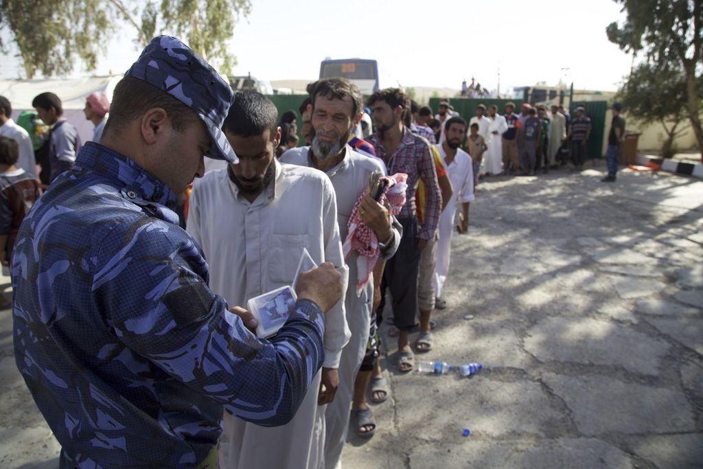 Ein irakischer Polizist kontrolliert eine Gruppe von Zivilpersonen, die sich an einem Sammelpunkt für Geflohene in einem Vorort von Tal Afar eingefunden haben. Die letzte vom IS beherrschte Stadt des Irak soll zu 90 Prozent zurückerobert sein. (Foto: Keystone/AP, Valint Szlanko)
